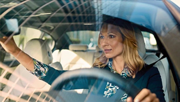 A woman adjusts her rearview mirror from the driver's seat